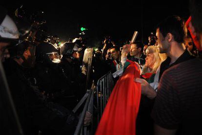 Un grupo de manifestantes trata de derribar una valla frente a la polic&iacute;a esta noche en Sof&iacute;a.