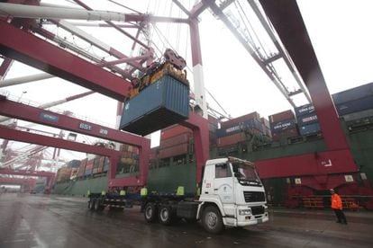 Un operari observa les tasques de càrrega d'un contenidor en un camió en un port.