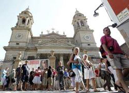 Un grupo de turistas pasa por delante de la fachada de la catedral de Pamplona.