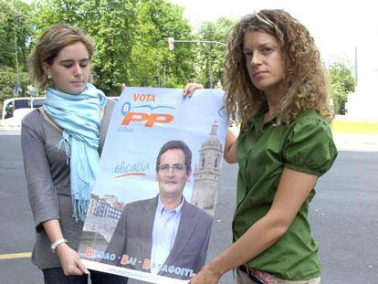 Nerea Alzola (derecha) y Virginia Arroyo sostienen un cartel de Antonio Basagoiti como los que estaban pegando cuando fueron agredidas.