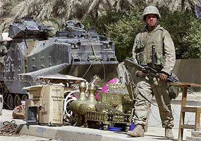 Un soldado de EE UU hace guardia junto a algunos objetos confiscados a saqueadores en un control de Bagdad.