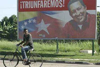 Un ciclista pasa ante un cartel de Hugo Chávez junto a las banderas de Cuba y Venezuela, ayer en La Habana.