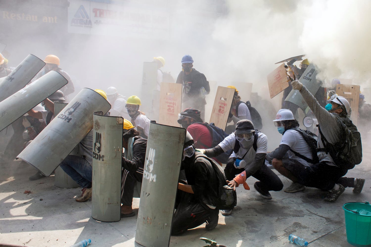 Manifestantes se protegen durante los enfrentamientos con la policía, en Yangón (Myanmar), este domingo.