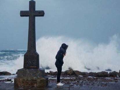 Una mujer junto a una cruz en la costa del desembarco de Normandía.