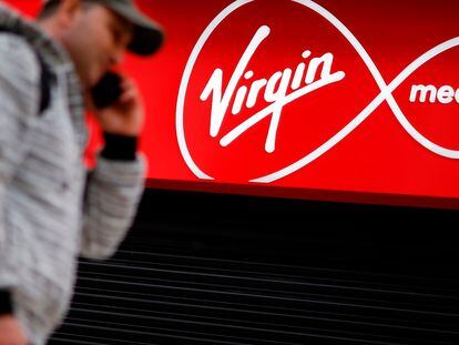 A person walks past a Virgin Media mobile phone store, closed-down due to the COVID-19 pandemic, in London on May 4, 2020. - Spanish group Telefonica on Monday said it was in talks with US cable giant Liberty Global to merge their telecoms operations in the UK.  In a statement, Madrid-based Telefonica said it was in "talks... about a possible integration" of its O2 mobile business and Liberty's Virgin Media that provides a mix of telecoms and television services, while providing caution over a deal ending up being struck. (Photo by Tolga Akmen / AFP)