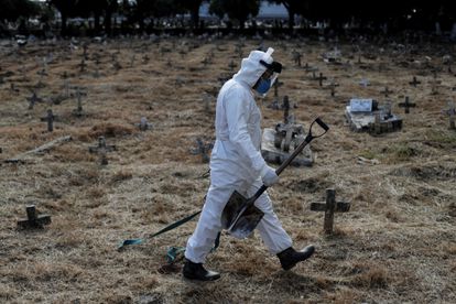 Un sepulturero camina por las tumbas del cementerio de Cajú (Río de Janeiro, Brasil) después de finalizar el entierro de una persona que se sospecha pudo morir de Covid-19.