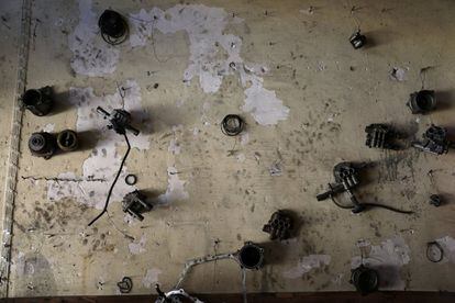 Partes mecánicas cuelgan de una pared de un taller abandonado.