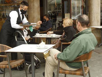 Un camarero atiende a varios clientes en la terraza de un bar en Palma, Mallorca (Islas Baleares).