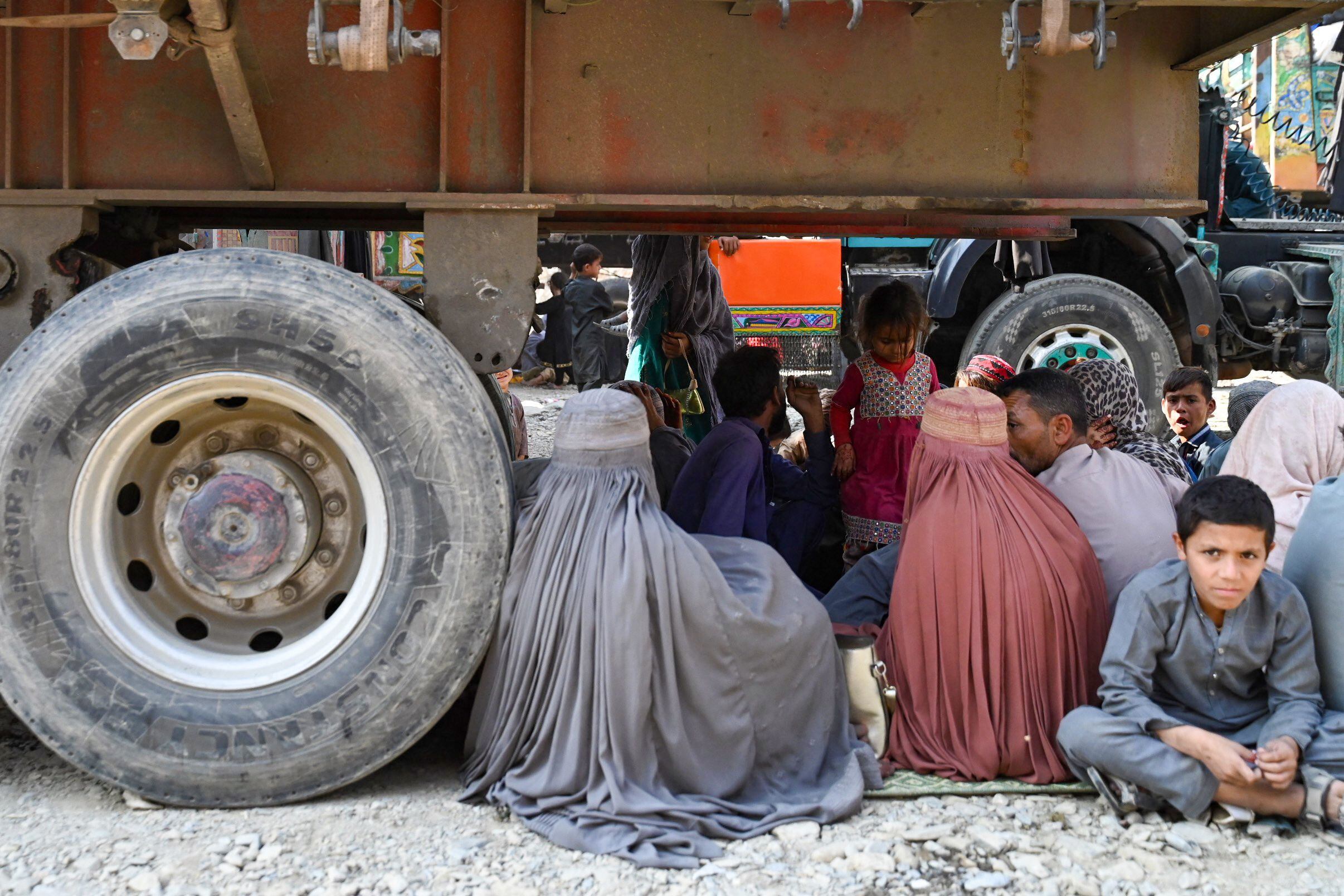 Varios afganos se sientan este lunes bajo un camión, a su llegada a Torkham (en la provincia paquistaní de Nangarhar), que está en la frontera entre ambos países. 