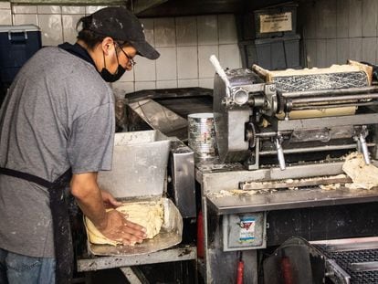 Un hombre produce tortillas en un local.