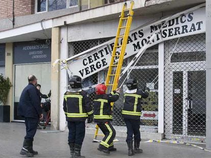 Un grupo de bomberos retira el letrero de un centro médico en Barcelona
