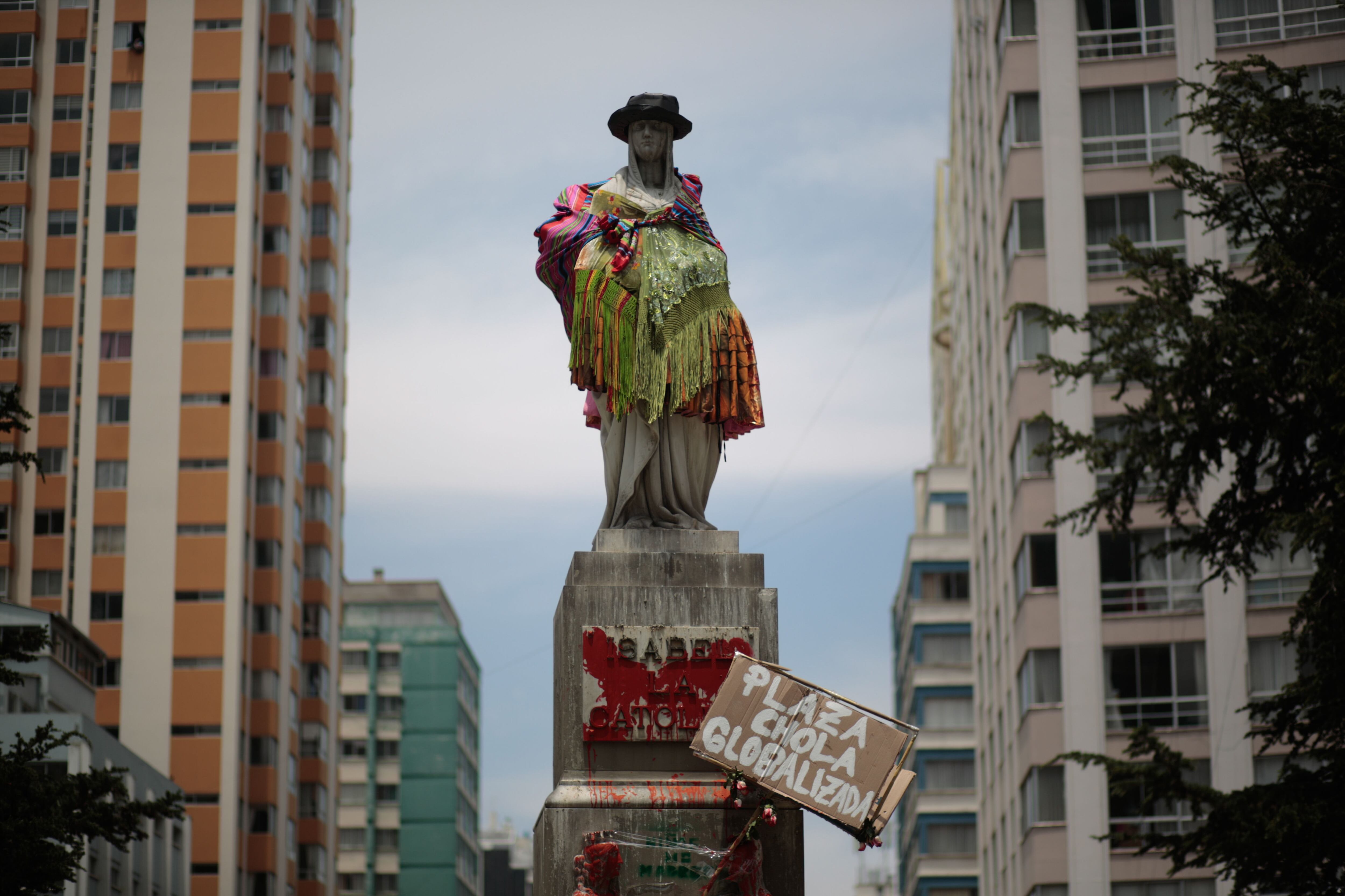 La estatua de la reina Isabel La Católica se ve vestida de cholita durante una protesta convocada por el grupo feminista 