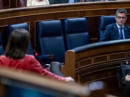 La ministra de Defensa, Margarita Robles, de espaldas, y el ministro de Presidencia, Félix Bolaños, en el hemiciclo del Congreso.