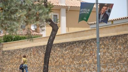 Una vecina de Dos Hermanas (Sevilla) pasea junto a un cartel electoral del PP.