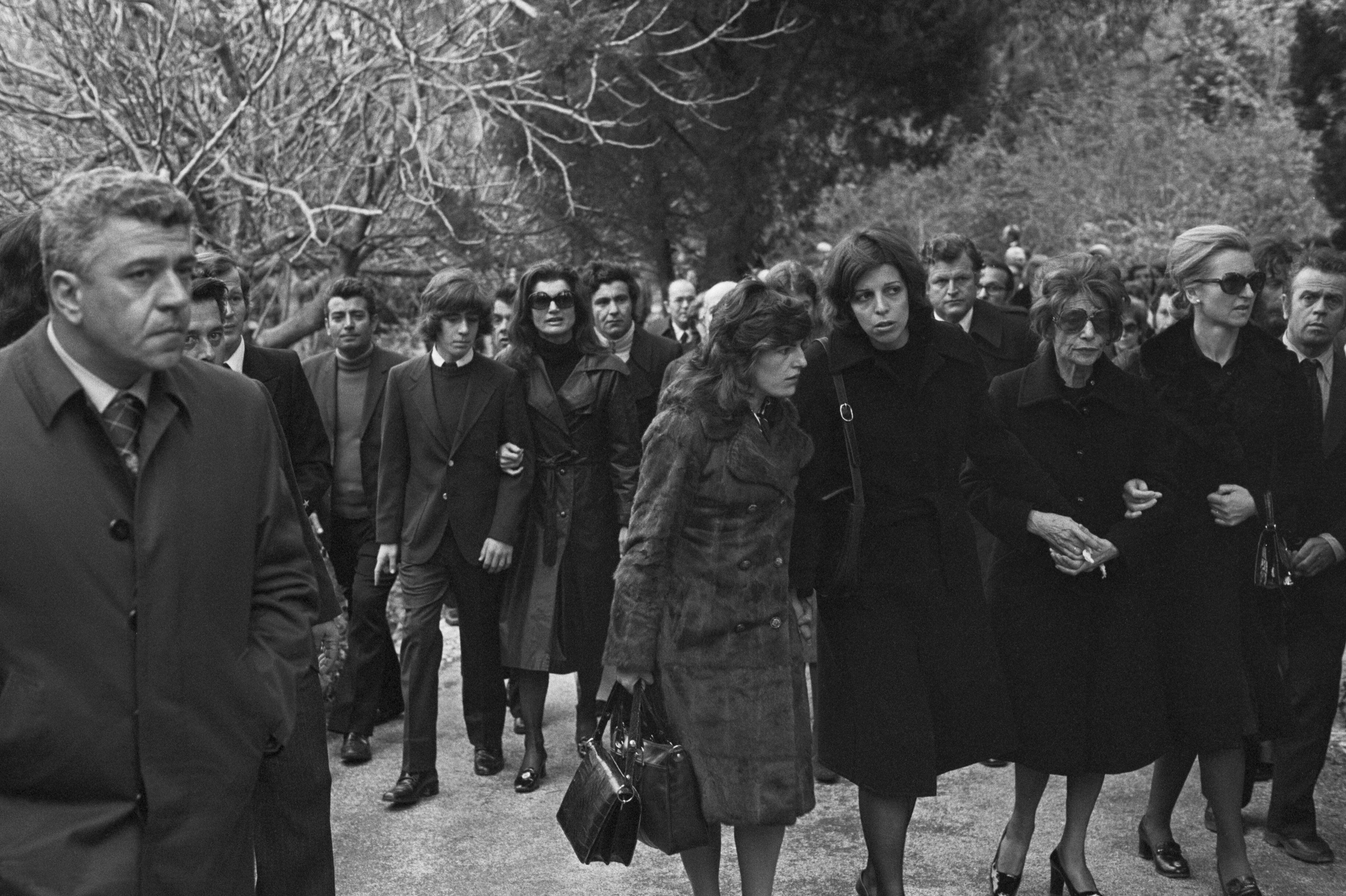 Cristina Onassis, en primera fila, y Jacqueline Onassis, en segunda línea, acompañada de su hijo John-John, durante el funeral de Aristóteles Onassis en la isla de Skorpios, en Grecia.