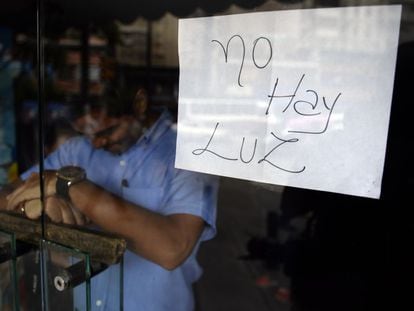 Un empleado, tras la puerta de un comercio cerrado en Caracas.