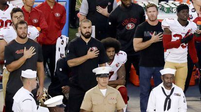 Colin Kaepernick espera sentado mientras suena el himno estadounidense antes de un partido de pretemporada de los San Francisco 49ers.