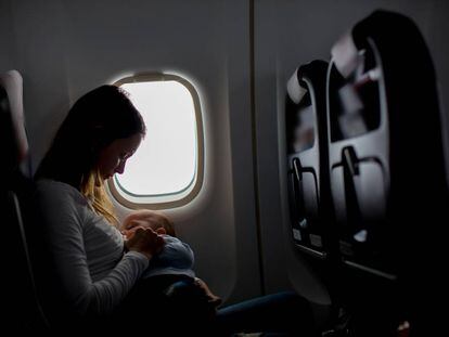 Una mujer amamanta a su bebé en un avión.