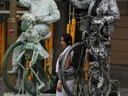 Una mujer se fotografía junto a dos estatuas humanas en la Rambla.