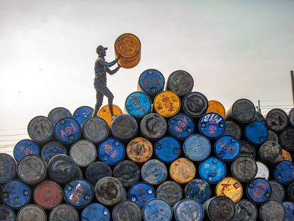Un trabajador apila barriles de petróleo reciclados en la localidad india de Narayanganj.
