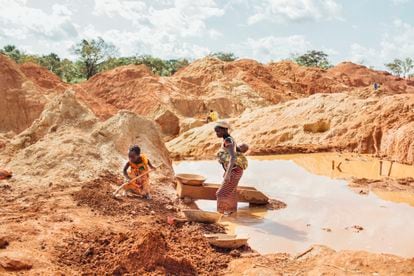 Una madre con su bebé en la espalda y su hija mayor trabajan buscando oro en una mina ilegal en Beke Route, este de Camerún