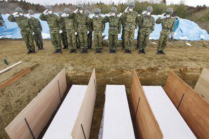 Miembros de las fuerzas de seguridad japonesas saludan tras el entierro de varias víctimas del terremoto y el posterior tsunami.