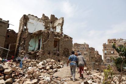 Dos hombres pasan frente a una casa destruida por un ataque aéreo en el casco antiguo de Saná, capital de Yemen, el pasado 8 de agosto de 2018. Unos 2.600 civiles fueron asesinados en aquel país en 2017 en el contexto del conflicto, según datos de la ONU.