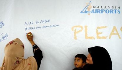 Una familia malasia escribe mensajes y oraciones en una pared en Kuala Lumpur. 