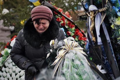 Una mujer llora ante la tumba de un familiar en el cementerio de Bucha. 