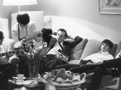John Lennon toca la guitarra ante los otros beatles y su mánager Brian Epstein en un hotel de París.