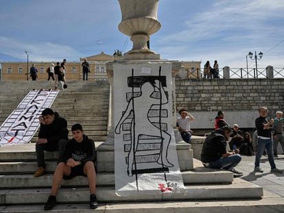 Jóvenes posan a lado de una pancarta con la palabra "criminales" y otra con un dibujo que representa a una víctima del accidente de tren frente al Parlamento griego, el pasado viernes.