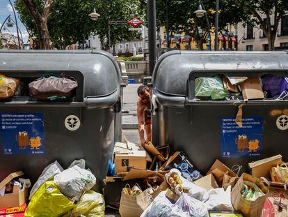 Un joven deja basura entre los contenedores de reciclaje en la plaza de Tirso de Molina de Madrid.