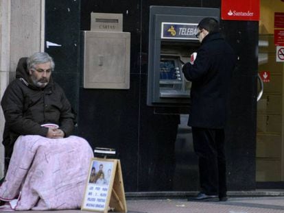 Un mendigo sentado al lado de un cajero, en Madrid. 