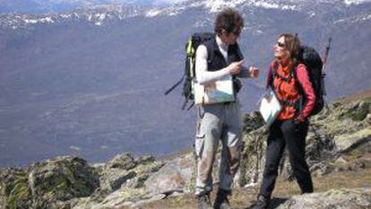 Dos excursionistas, con el Pico del Lobo, en la sierra de Ayll&oacute;n,  al fondo.  