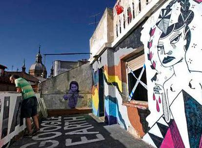 La terraza del quinto piso del Patio Maravillas, con los tejados de Malasaña de fondo, sirve de escenario para las obras temporales del taller de arte urbano.
Arriba, las escaleras decoradas con los restos de una exposición. A la derecha, la entrada.