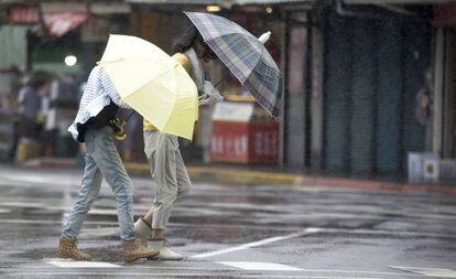 Dos mujeres taiwanesas caminan este viernes bajo la lluvia y los fuertes vientos.