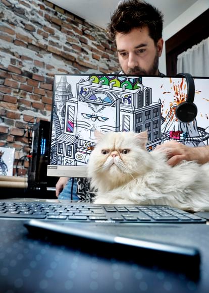 Sur l'écran de l'ordinateur, vous pouvez voir la première œuvre qu'Arrés a téléchargée sur MakersPlace, The Tiñín Cat Kingdom, dédiée à son chat, Tiñín, qui pose devant lui.