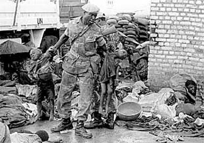 Un soldado retira dos niños muertos de entre decenas de cadáveres para preparar una fosa común, el 22 de abril de 1995.