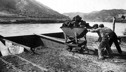 Unos trabajadores cargan un barco de carb&oacute;n en el r&iacute;o Ebro en los alrededores de Mequinenza a principios del siglo XX.