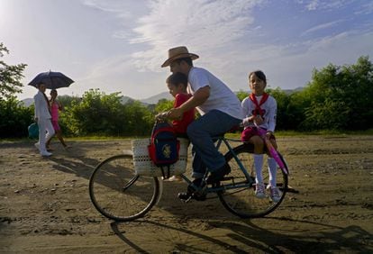 Un padre lleva a sus hijos al colegio por la carretera cercana a la finca de los hermanos Castro en Birán (Cuba).
