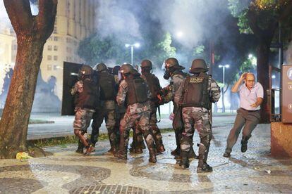 Un hombre corre para protegerse ante la irrupción de la policía militar brasileña que ha empelado gases lacrimógenos para dispersar a los manifestantes.