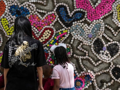 Unos niños pegan tapones de botellas de plástico en el llamado Muro del Amor, en el parque de Los Caobos, en Caracas, Venezuela, el 23 de diciembre de 2022. Esta es una iniciativa de la ONG Oko Spire para reciclar los tapones y evitar que contaminen el medio ambiente.