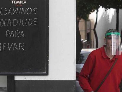 Un trabajador protegido con una máscara reparte en un bar de Córdoba.