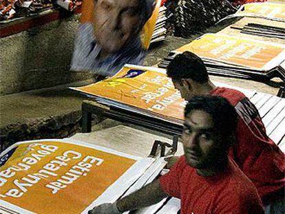 Trabajadores paquistaníes de la empresa Marc Martí manipulan carteles de la campaña de CiU.