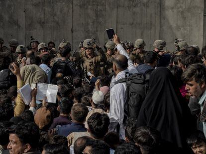 Un hombre sujeta su pasaporte delante de los militares que guardan el aertopuerto de Kabul.