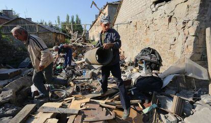 Tres hombres retiran escombros de sus casas tras un bombardeo en la región de Donetsk.