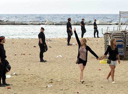 Dos jóvenes se despiden de los policías que desalojan la playa, ayer en Barcelona tras la verbena de Sant Joan.