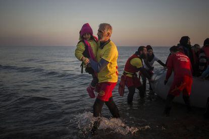 Enrique Álvarez ayuda el lunes a bajar a una niña refugiada en una playa cercana a la ciudad de Mytilene, en la isla de Lesbos.