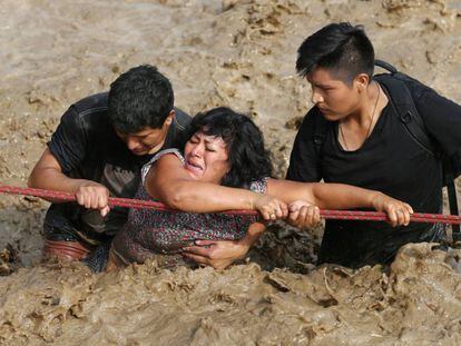 Una mujer es ayudada a salir de una riada en Huachipa, Perú.