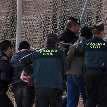Agentes de la guardia civil preceden a expulsar por la valla a dos migrantes que acababan de saltar la valla de Melilla. 2 de diciembre de 2014. Foto Antonio Ruiz.